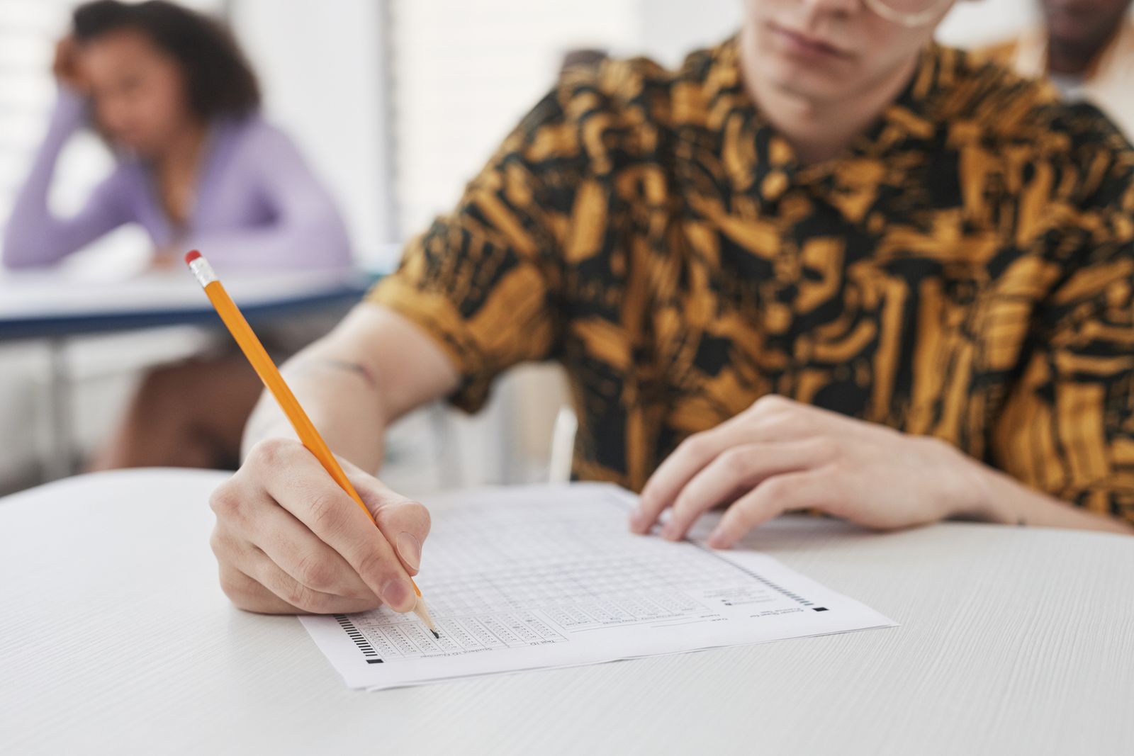 Close-up of a student writing on an exam sheet with a pencil, focused on a timed test