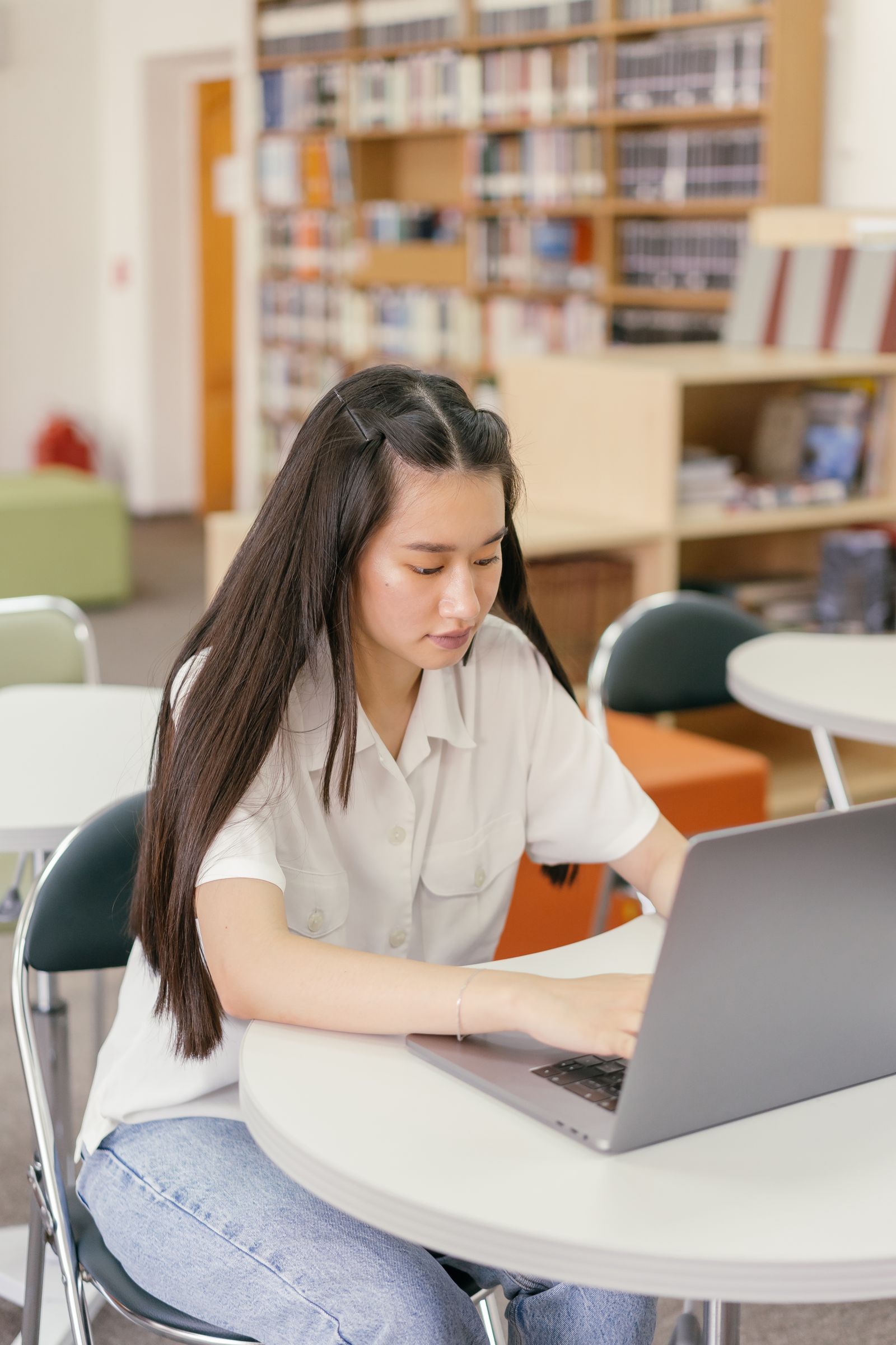 Focused student reviewing notes and a laptop in a library setting